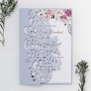 Detail of laser-cut floral pattern on dusty blue wedding invitation card with inserts