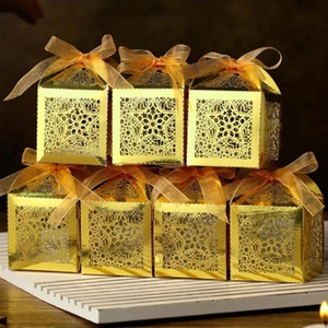 Detail of laser-cut star and moon patterns on golden party candy gift boxes with ribbons
