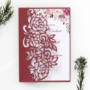 Macro detail of laser-cut burgundy rose patterns on high-end wedding invitation cards