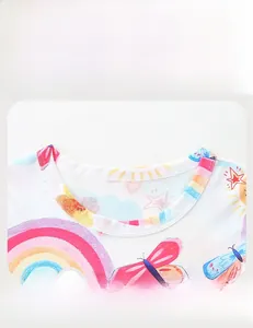 Détail du col rond doux avec motifs arc-en-ciel et papillon sur la robe pour filles