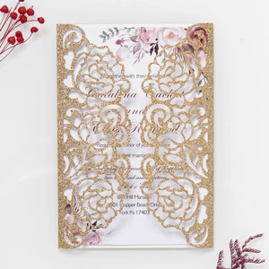 Close-up of laser-cut glitter rose invitation with floral print insert on white surface