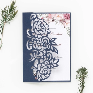 Close-up of laser-cut floral invitation cover with watercolor rose inner card details