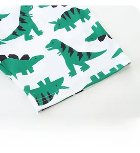 Détail de l'ourlet de pantalon en coton pour enfant avec motifs dinosaures verts