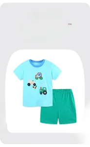 Detail of cotton kids set featuring a blue t-shirt with tractor embroidery and green shorts