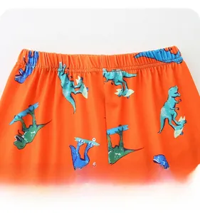 Detail of elastic waistband and cartoon dinosaur print on toddler orange summer shorts