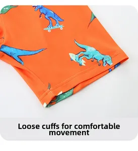 Close-up of bright orange kids shorts featuring cartoon dinosaur skateboard prints