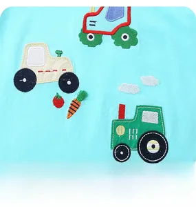Close-up of tractor embroidery and cotton fabric on a light blue toddler clothing set
