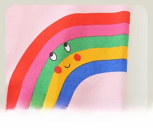 Gros plan d'un imprimé arc-en-ciel avec un visage souriant sur tissu en coton rose