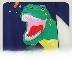 Détail de la broderie dinosaure verte sur un pull en maille de coton bleu marine