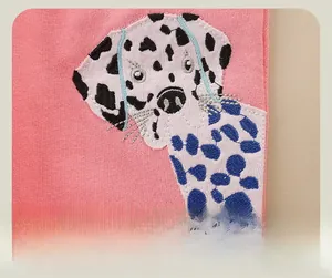 Détail d'un pantalon en coton rose avec broderie de chien en 3D et coutures soignées