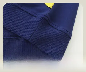 Gros plan détaillé de l'ourlet côtelé bleu foncé avec coutures précises sur ce pull enfant