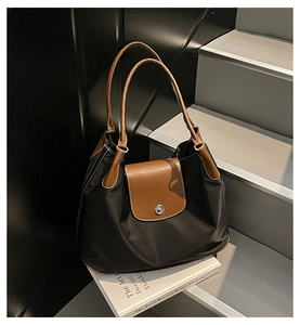 Detail of minimalist tote bag with smooth satin body and brown leather handles