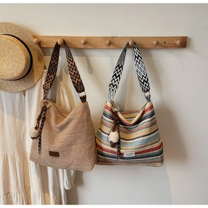 Dettaglio di borse tote in paglia intrecciata con tracolle geometriche e nappe