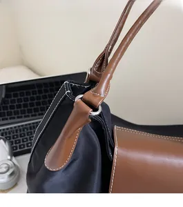 Close-up of black nylon tote bag with brown leather handles and silver hardware