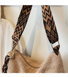 Dettaglio borsa in paglia intrecciata con tracolla larga a motivi geometrici bohémien