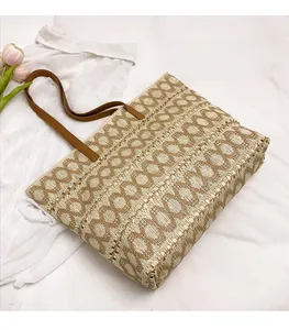 Detail of woven straw tote bag featuring brown leather straps and geometric circular patterns