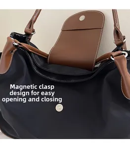 Detail shot of the magnetic snap closure on a black nylon tote with contrast stitching