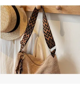 Dettaglio della borsa tote in paglia con tracolla geometrica e nappa ornamentale
