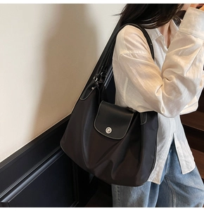 Detail of large black shoulder bag with white contrast stitching and silver metal buckle