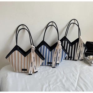 Detailed view of three striped canvas tote bags with V-shaped cut and leather handles