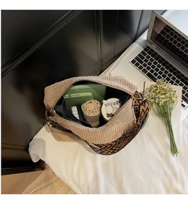 Vista dall'alto di una borsa in paglia intrecciata con interno spazioso e oggetti vari