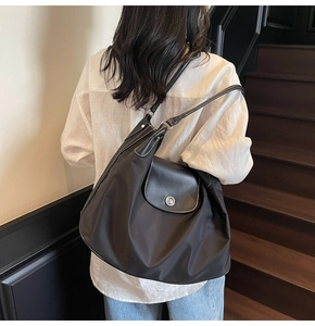 Detail of black tote bag featuring contrast stitching and silver metal buckle closure