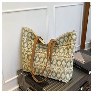 Detail of geometric woven straw tote bag with brown leather straps on luggage
