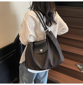 Detail of a large brown tote bag with contrast stitching and silver metal buckle closure