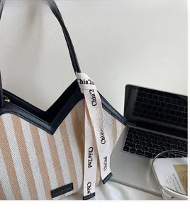 Detail of canvas tote bag showing black leather trim and decorative lettered strap
