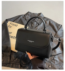 Detail of black leather handbag with dual texture stitching and elegant silver hardware