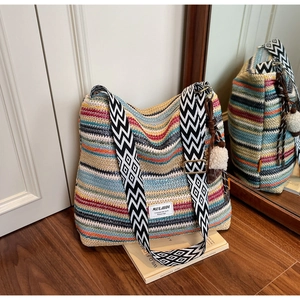 Detail of bohemian striped woven bag featuring geometric strap and colorful tassel charm