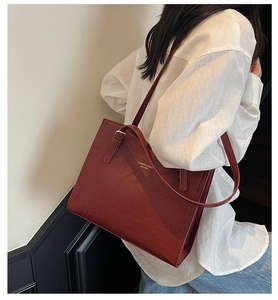 Close-up of a vintage red faux leather tote bag showing textured grain and gold lettering