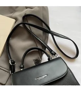 Detail of black leather handbag featuring contrast pebble grain and smooth flap textures