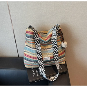 Detail of colorful striped straw bag with geometric strap and bohemian tassel ornament