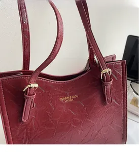 Detail of burgundy patent leather tote with gold hardware and embossed fashion text