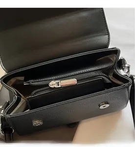 Detail view of black pebble leather handbag interior with zipper pocket and silver magnetic closure