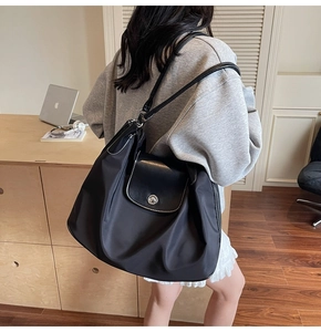 Detail of black nylon tote bag with white contrast stitching and silver metal lock