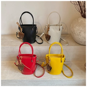 Detail of four colorful leather bucket bags on stone steps showing handles and straps