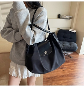 Classic black nylon tote bag with leather flap detail worn by a model in casual setting