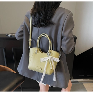 Détail du sac à main en cuir grainé avec nœud en dentelle et perle sur un mannequin