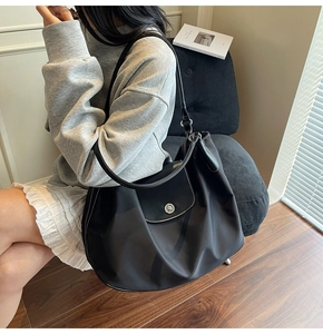 Detail of black tote bag featuring white contrast stitching and silver metal buckle