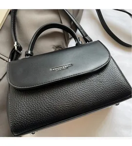 Detail of black textured leather handbag with fashion embossed text and adjustable strap