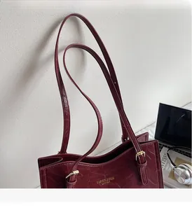 Detail of burgundy leather tote showing pleated texture and gold embossed lettering