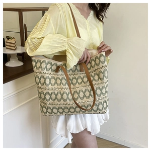 Close-up of woven straw tote bag with geometric patterns and brown leather straps