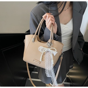 Sac cabas kaki avec nœud en dentelle et perles porté par un mannequin en décor épuré