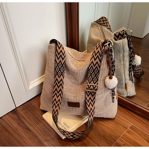 Detail of woven straw tote bag featuring geometric patterned strap and brand logo