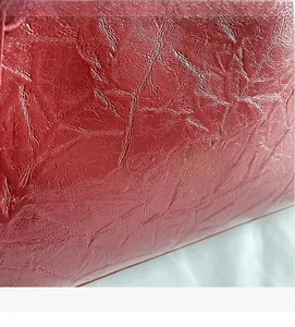 Macro shot of dark red leather material with natural texture and glossy finish