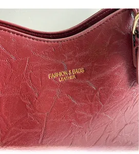 Close-up of burgundy leather tote bag showing gold logo and fine stitching details