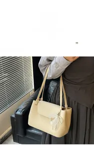 Detail of off-white lychee leather shoulder bag with lace pearl bow charm decoration