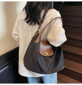Detail of classic nylon tote bag featuring brown leather flap and silver buckle on model